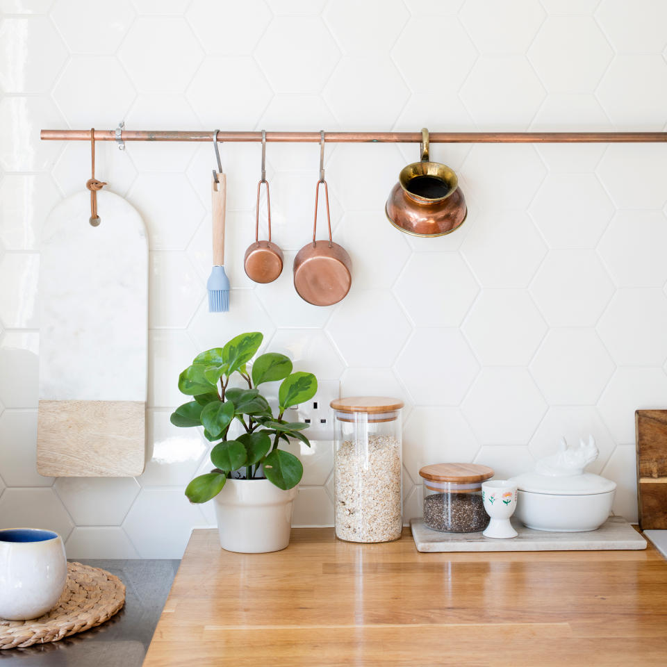 Kitchen with white hexagonal splashback and brass rail storage