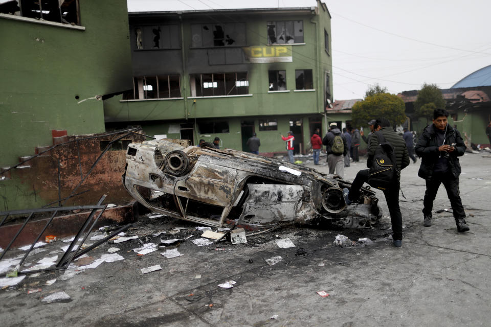 People gather outside a police station attacked by supporters of former President Evo Morales in El Alto, outskirts of La Paz, Bolivia, Tuesday, Nov. 12, 2019. Bolivia faced its worst unrest in decades amid a political vacuum while Morales fled the country on a Mexican government plane late Monday, hours after stepping down following weeks of widespread protests fed by allegations of electoral fraud. (AP Photo/Natacha Pisarenko)