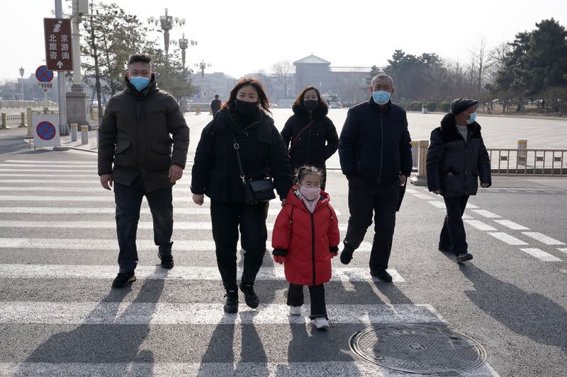 Tourists wearing masks walk to Tiananmen Square in Beijing