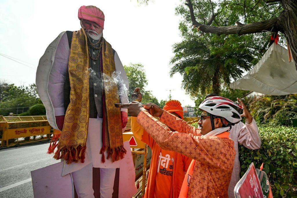 A supporter of Narendra Modi, India's Prime Minister and leader of Bharatiya Janata Party (BJP) performs rituals with Modi's cut-out outside the BJP headquarters in New Delhi 