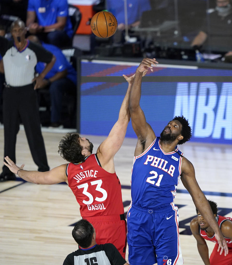 Toronto Raptors' Marc Gasol (33) and Philadelphia 76ers' Joel Embiid (21) go up for the opening tipoff during the first half of an NBA basketball game Wednesday, Aug. 12, 2020 in Lake Buena Vista, Fla. (AP Photo/Ashley Landis, Pool)