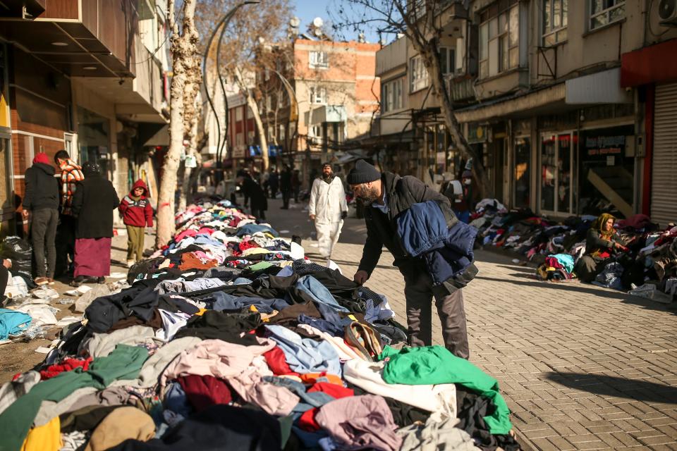 A man looks for clothing in Adiyaman, southern Turkey, Monday, Feb. 13, 2023. Thousands left homeless by a massive earthquake that struck Turkey and Syria a week ago packed into crowded tents or lined up in the streets Monday for hot meals as the desperate search for survivors entered what was likely its last hours.