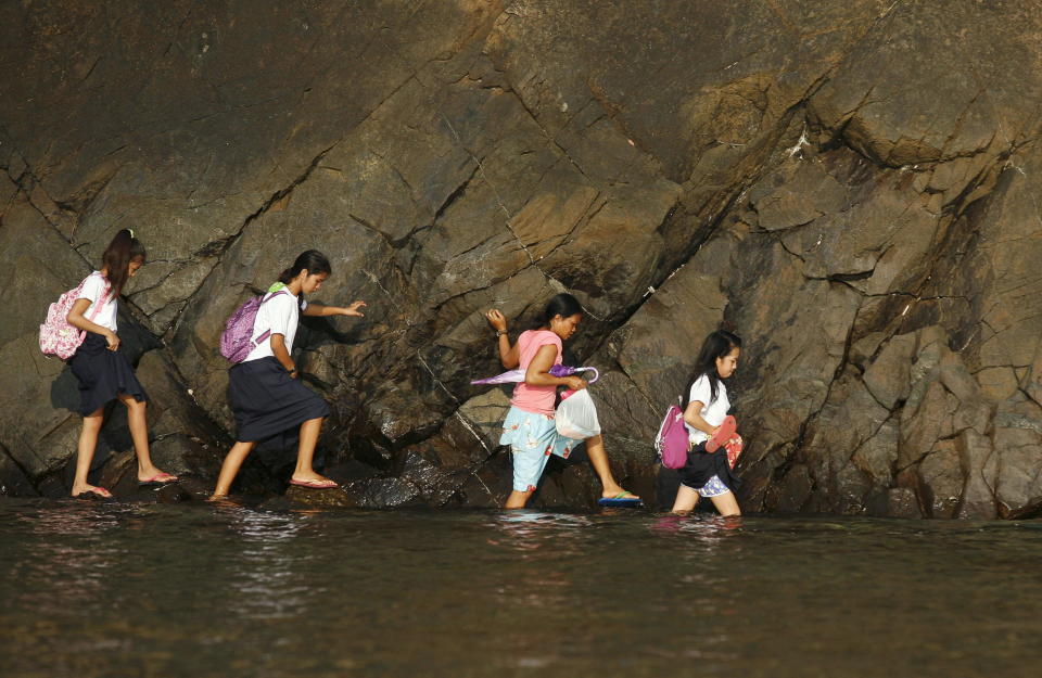 A woman accompanies some students as they wade in the shallow part of a rocky beach to their school to attend the first day of classes in Sitio Kinabuksan, Kawag village, Subic, Zambales Province, north of Manila June 1, 2015.&nbsp;