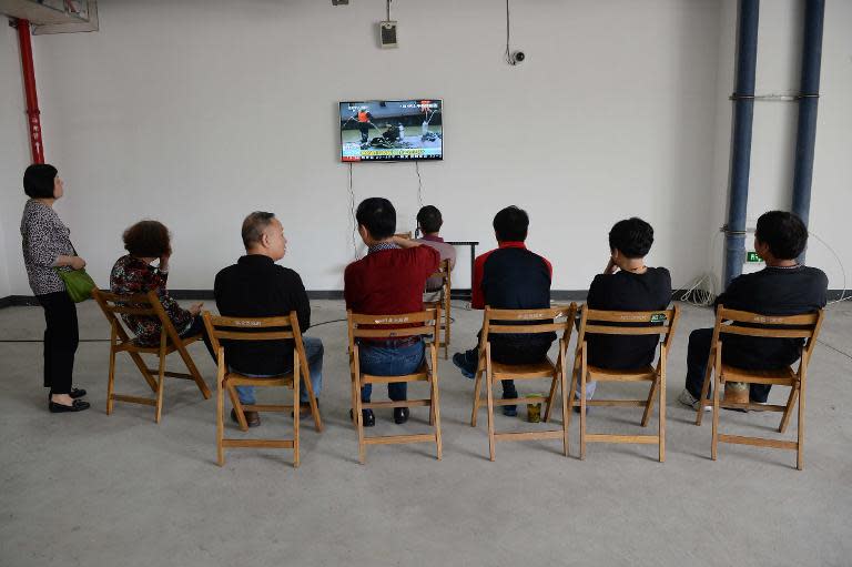 Relatives of passengers on board the sunk vessel Dongfangzhixing or "Eastern Star", watch a television news broadcast as they gather at a temporary reception centre in Shanghai on June 3, 2015