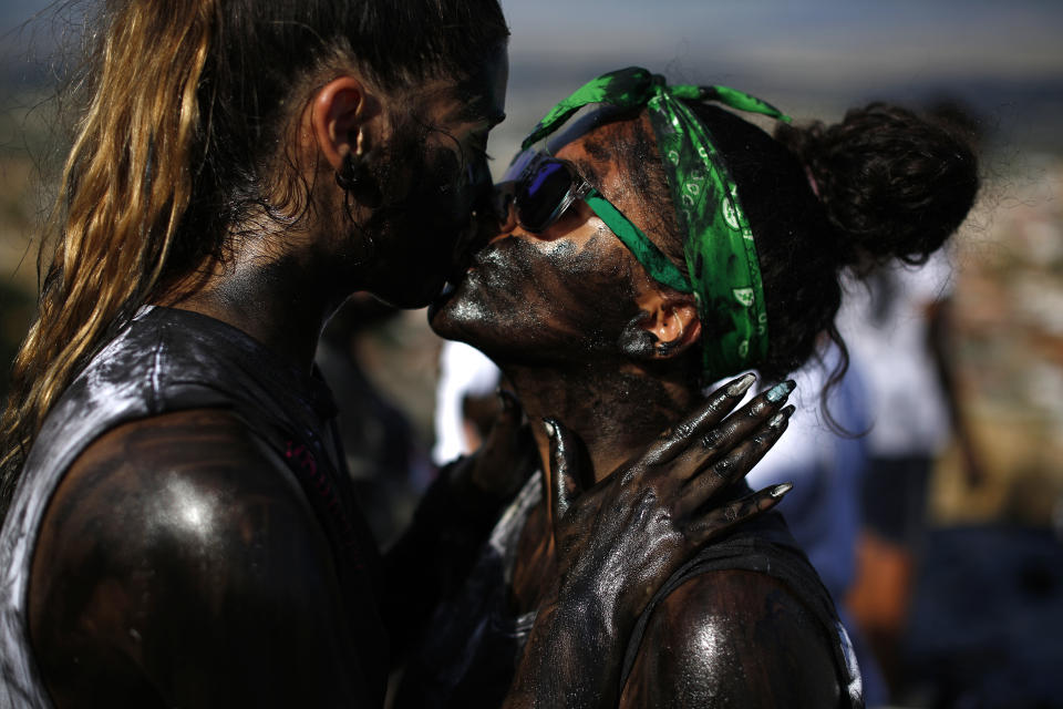 In this photo taken on Friday, Sept. 6, 2019, a couple painted with black grease kiss each other as they take part at the traditional festivities of the Cascamorras festival in Baza, Spain. During the Cascamorras Festival, and according to an ancient tradition, participants throw black paint over each other for several hours every September 6 in the small town of Baza, in the southern province of Granada. The "Cascamorras" represents a thief who attempted to steal a religious image from a local church. People try to stop him, chasing him and throwing black paint as they run through the streets. (AP Photo/Manu Fernandez)