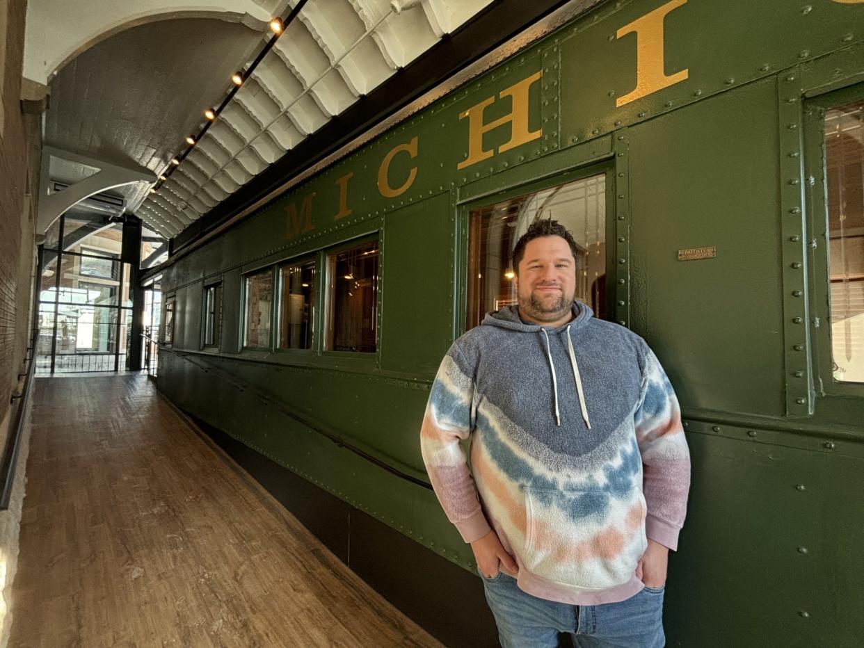 Bobcat Bonnie's owner Matt Buskard leans against the historic train car at the Michigan-based restaurant chain's eighth location, which is set to open its doors before the end of January off East Michigan Avenue in one half of the historic former Clara's Lansing Station in Lansing.