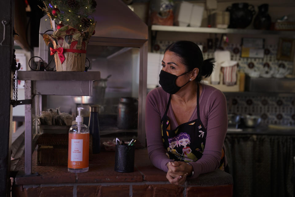 Debbie Briano, a fourth-generation owner of Mexican restaurant, El Rancho Grande, waits for customers in her restaurant on Olvera Street in downtown Los Angeles, Wednesday, Dec. 16, 2020. Even as the December light casts long shadows over the market, Briano is not giving up. She's serving takeout food and is paying five employees, including brothers who have worked there 55 years and 48 years each, but not herself. (AP Photo/Jae C. Hong)