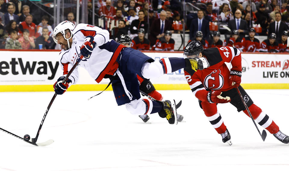 Washington Capitals left wing Alex Ovechkin (8) shoots the puck in front of New Jersey Devils defenseman Colin Miller (24) during the first period of an NHL hockey game Friday, Nov. 10, 2023, in Newark, N.J. (AP Photo/Noah K. Murray)