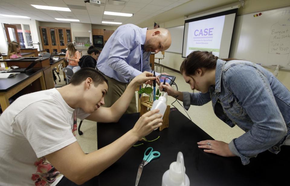 Chase Martin, left, and Harley Brown work with teacher Chris Kaufman on a project during Plant and Soil Science class at Beech Grove High School Wednesday, April 30, 2014, in Indianapolis. High school agriculture programs sprouting across the nation’s Corn Belt are teaching teenagers, many of them in urban environments, that careers in the field often have nothing to do with cows and plows. (AP Photo/Darron Cummings)