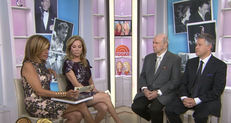 hoda and kathie lee looking at a note card while the guests sit nearby