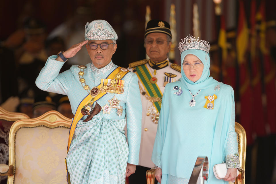 Malaysia's King Sultan Abdullah Sultan Ahmad Shah salutes next to Queen Tunku Azizah Aminah Maimunah and Prime Minister Mahathir Mohamad, center, during his welcome ceremony at Parliament House in Kuala Lumpur, Malaysia, Thursday, Jan. 31, 2019. Sultan Abdullah, ruler of central Pahang state, was named Malaysia's new king, replacing Sultan Muhammad V who abdicated unexpectedly after just two years on the throne. (AP Photo/Yam G-Jun)