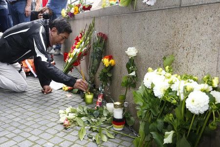 A man lights incense sticks near the Olympia shopping mall, where yesterday's shooting rampage started, in Munich, Germany July 23, 2016. REUTERS/Arnd Wiegmann