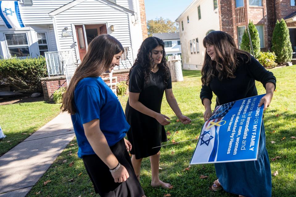 (From left) Liat Deykan, Ori Safra and Chavie Hagler put a sign in front of Hagler's Bergenfield home on Friday, October 13, 2023. Hagler and her friends are selling lawn signs to help raise awareness of people in Israel who were kidnapped and who are missing.
