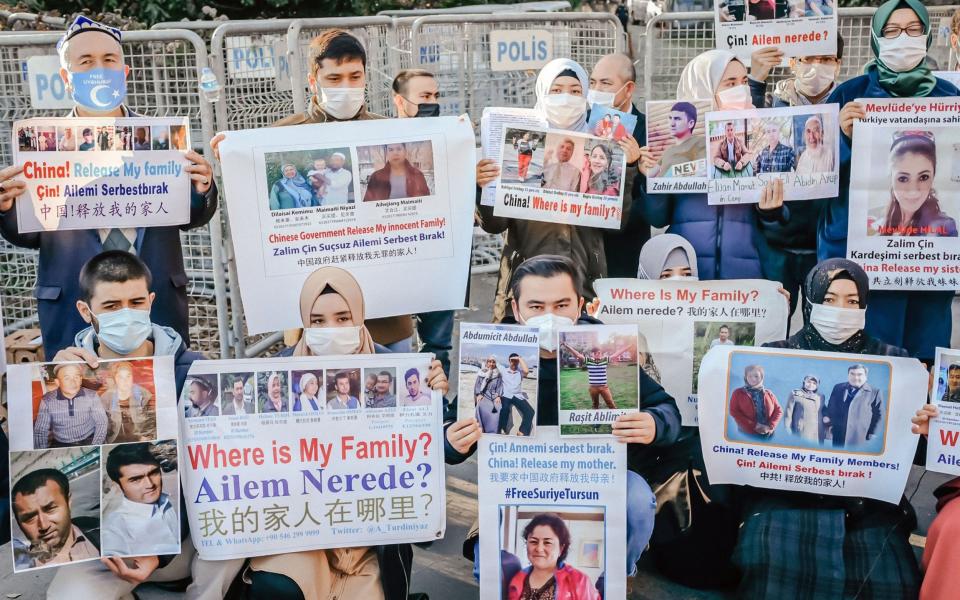 Members of the Muslim Uyghur minority hold placards as they demonstrate in front of the Chinese consulate - AFP