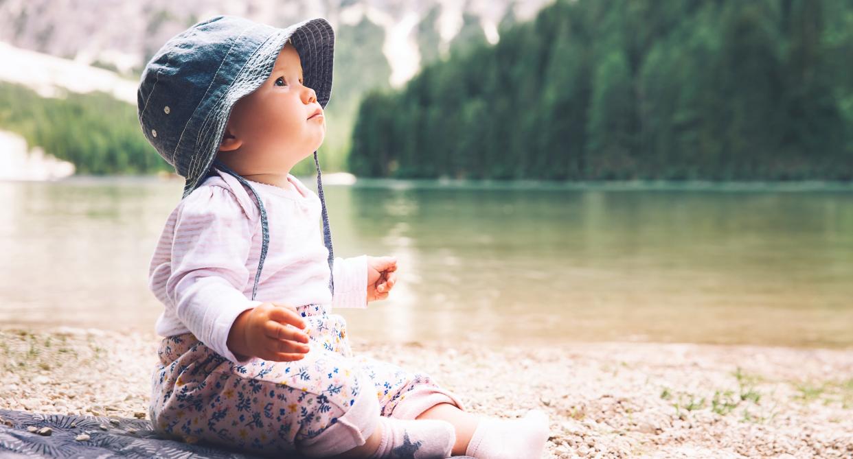 A baby sitting on shore of a lake as a new study has found the nature-inspired baby names on the rise