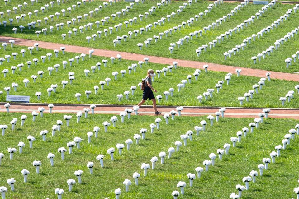 A pedestrian walks through a memorial adorned with white flowers and dedicated for victims of gun violence, Tuesday, Aug. 24, 2021, at Independence Mall in Philadelphia.