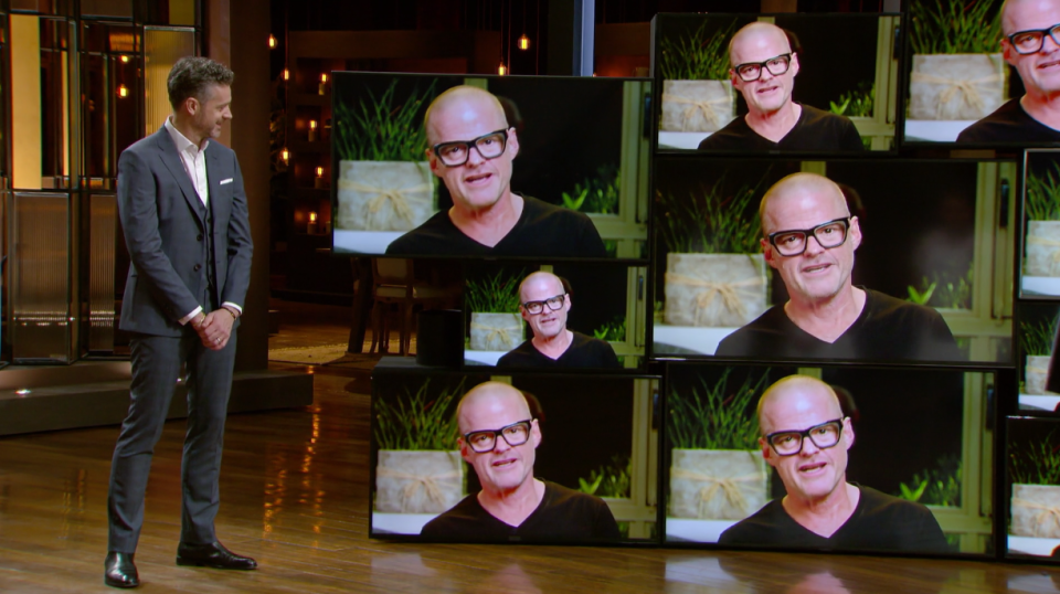 MasterChef judge Jock Zonfrillo stands next to a wall of televisions showing a video of Heston Blumenthal