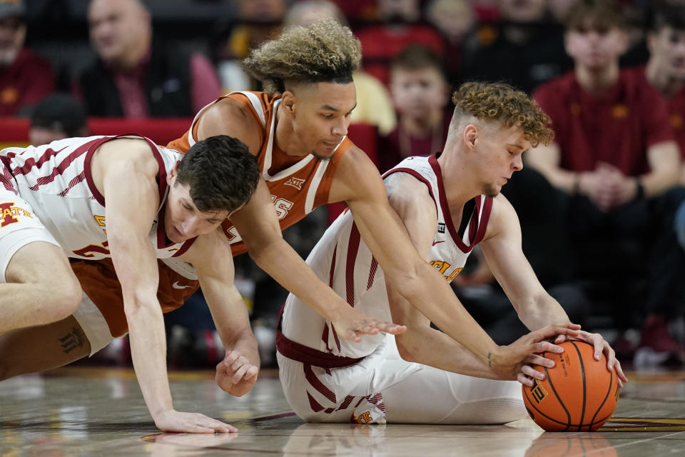 Texas forward Tre Mitchell, center, fights for a loose ball with Iowa State guard Caleb Grill, left, and forward Aljaz Kunc, right, during the first half of an NCAA college basketball game, Saturday, Jan. 15, 2022, in Ames, Iowa. (AP Photo/Charlie Neibergall)