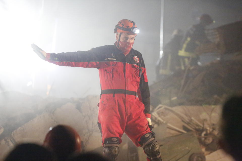In this photo provided by Turkey's IHH humanitarian aid group, a member of rescue services, guides others during searching for survivors in the debris of a collapsed building in Izmir, Turkey, early Saturday, Oct. 31, 2020. Rescue teams continue ploughing through concrete blocs and debris of collapsed buildings in Turkey's third largest city in search of survivors of a powerful earthquake that struck Turkey's Aegean coast and north of the Greek island of Samos, Friday Oct. 30, killing dozens Hundreds of others were injured. (IHH via AP)