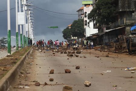 Opposition supporters are seen next to a roadblock on a street in Bambeto as they take part in a protest after opposition candidates called on Monday for the results of the election to be scrapped due to fraud, in Conakry October 13, 2015. REUTERS/Luc Gnago