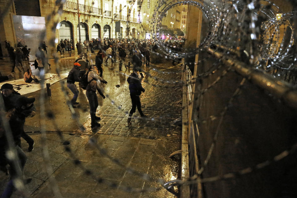 Anti-government protesters throw stones at the riot police during ongoing protests in Beirut, Lebanon, Wednesday, Jan. 22, 2020. Lebanon's new government held its first meeting Wednesday, a day after it was formed following a three-month political vacuum, with the prime minister saying his Cabinet will adopt financial and economic methods different than those of previous governments.(AP Photo/Bilal Hussein)