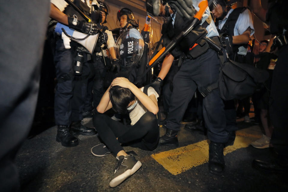 A protester covers himself near Hong Kong police officers in anti riot gear during a rallying against the proposed amendments to extradition law at the Legislative Council in Hong Kong during the early hours of Monday, June 10, 2019. The extradition law has aroused concerns that this legislation would undermine the city's independent judicial system as it allows Hong Kong to hand over fugitives to the jurisdictions that the city doesn't currently have an extradition agreement with, including mainland China, where a fair trial might not be guaranteed. (AP Photo/Kin Cheung)