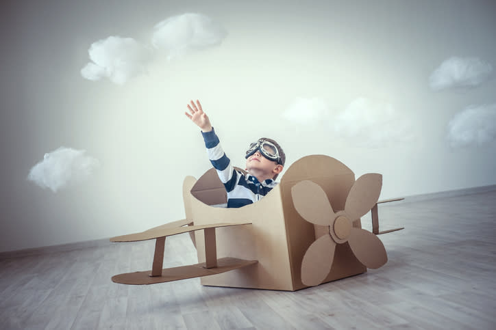 A child playing in a cardboard airplane.