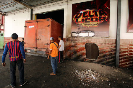 Workers stand next to a truck at a liquor distributor after it was looted in San Felix, Venezuela January 24, 2019. REUTERS/William Urdaneta