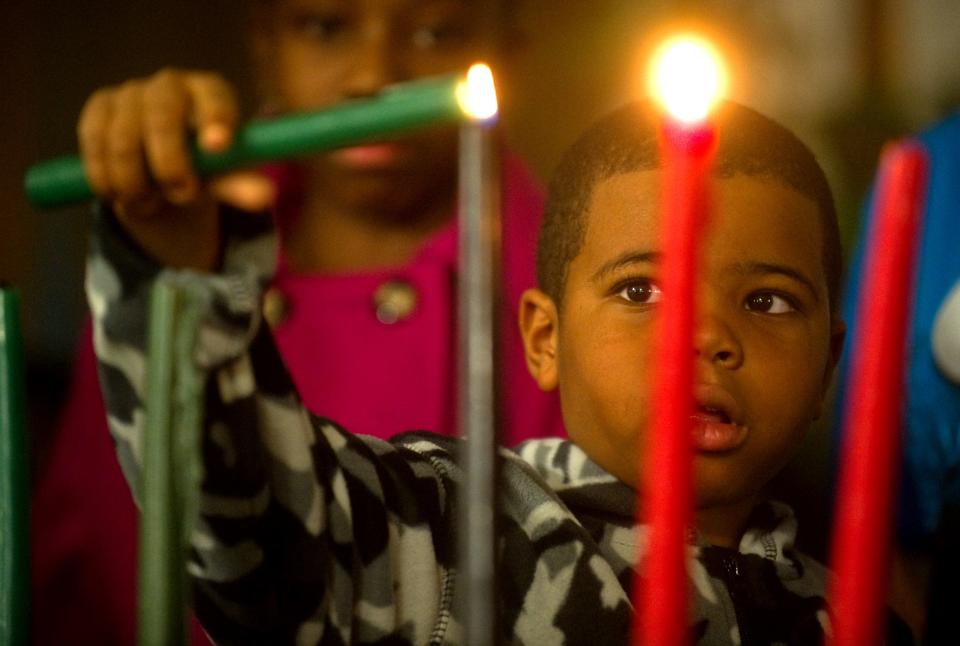 6-year-old Kristian Freeman lights one of the Kwanzaa candles at the Black Employees Association of Stockton Unified School District's Kwanzaa celebration at The Rock Senior and Youth Center in downtown Stockton.