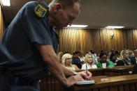 Reeva Steenkamp's mother June (C, in white) looks on while a South African policeman takes notes in court as Olympic and Paralympic track star Oscar Pistorius (not pictured) attends the hearing of his trial for the murder of his girlfriend Steenkamp at the North Gauteng High Court in Pretoria March 18, 2014. Pistorius is on trial for murdering Steenkamp at his suburban Pretoria home on Valentine's Day last year. REUTERS/Marco Longari/Pool (SOUTH AFRICA - Tags: SPORT CRIME LAW ATHLETICS)