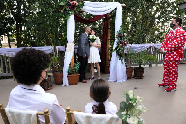 <p>Mario Tama/Getty</p> Manuela Torres and Sergio Flores as owner Alan Katz (R) presides over their wedding ceremony at Cute Little Wedding Chapel on Valentine