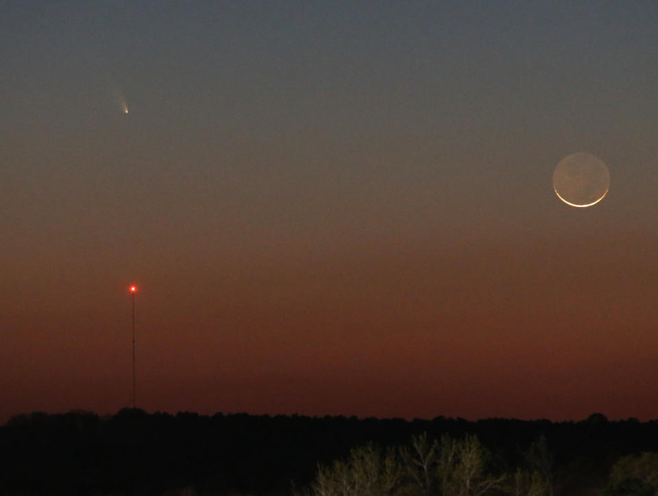 Comet Pan-STARRS is seen over the tower on the left as a 1 day waxing crescent Moon is seen setting in the Western sky on Tuesday, March 12, 2013. The dark side of the Moon is lit by reflected light from the Earth, and is called Earthshine. (AP Photo/Dr. Scott M. Lieberman)