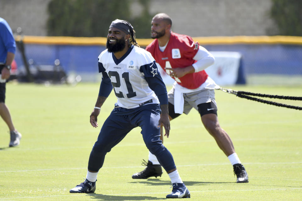 Dallas Cowboys running back Ezekiel Elliott (21) and quarterback Dak Prescott warm up before practice at the NFL football team's training camp in Oxnard, Calif., Thursday, July 22, 2021. (AP Photo/Michael Owen Baker)