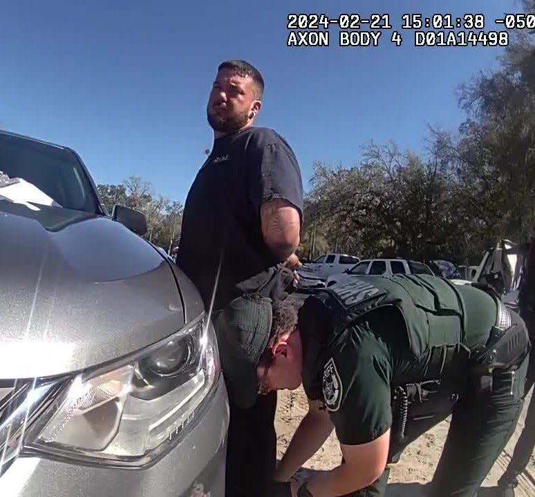 An officer searches Brad Perry Wednesday, Feb. 21, 2024.