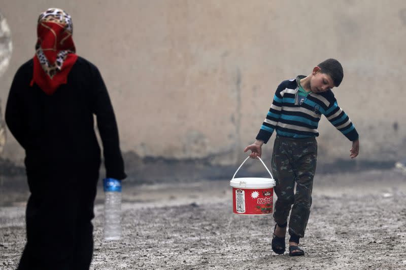 Internally displaced boy carries a bucket filled with water in Azaz