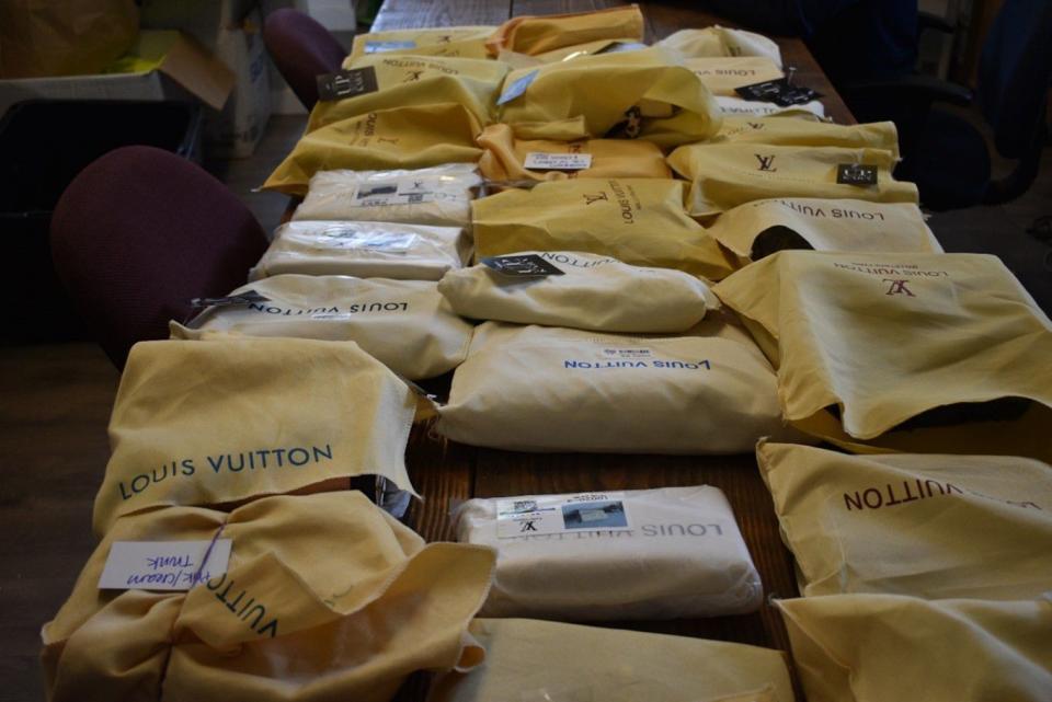 A table full of counterfeit Louis Vuitton handbags.