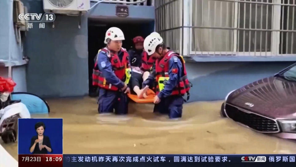 In this image taken from video footage run by China's CCTV, rescuers evacuate a resident following a flood in a village in eastern China's Zhejiang province on Sunday, July 23, 2023. Floods caused by heavy rain hit eastern China, leaving at least five dead and three missing while over 1,500 people were evacuated, state media reported on Sunday. (CCTV via AP)