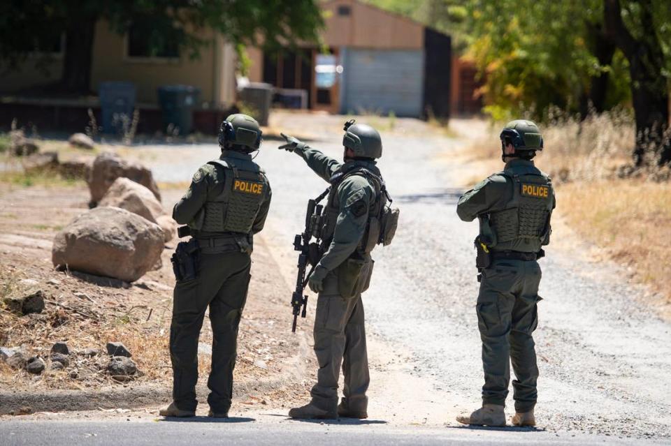 A Placer County sheriff’s deputy, joined by two police officers, points toward a home on Greenbrae Road in Rocklin on Sunday, July 9, 2023, after a potential sighting of Mahany Park murder suspect Eric James Abril, who escaped early Sunday from Roseville hospital.