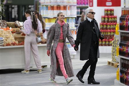 German designer Karl Lagerfeld (R) and model Cara Delevingne appear at the end of his Fall/Winter 2014-2015 women's ready-to-wear collection show for French fashion house Chanel at the Grand Palais transformed into a "Chanel Shopping Center" during Paris Fashion Week March 4, 2014. REUTERS/Stephane Mahe