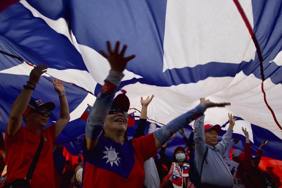 Supporters of Han Kuo-yu, Taiwan's 2020 presidential election candidate of the KMT or Nationalist Party, pass under a giant Taiwanese flag during a campaign rally in southern Taiwan's Kaohsiung city on Friday, Jan 10, 2020. Taiwan will hold its presidential election on Jan. 11, 2020. (AP Photo/Ng Han Guan)