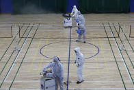 Workers in protective suits spray disinfectant as a precaution against the COVID-19 at an indoor gymnasium in Seoul, South Korea, Tuesday, Feb. 25, 2020. China and South Korea on Tuesday reported more cases of a new viral illness that has been concentrated in North Asia but is causing global worry as clusters grow in the Middle East and Europe. (AP Photo/Lee Jin-man)