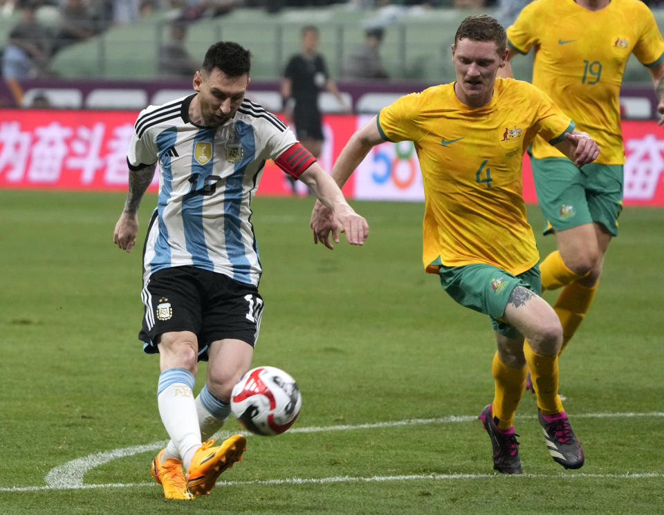 Argentina's Lionel Messi, left, shoots the ball at the goal past Australia's Kye Rowles during the first half of their friendly soccer match at Workers' Stadium in Beijing, Thursday, June 15, 2023. (AP Photo/Mark Schiefelbein)