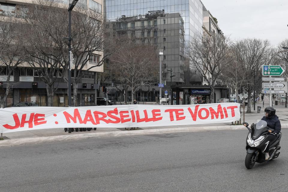 A man on a scooter looks over at a banner hung by Olympique de Marseille football club fans against the club's president Jacques-Henry Eyraud, that reads in French 'JHE: Marseille vomits you', a few hours before the Ligue 1 match against Rennes in the southern French city of Marseille on January 30, 2021.