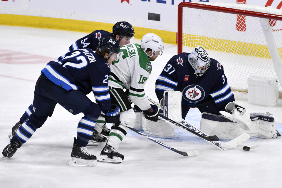 Winnipeg Jets' goaltender Connor Hellebuyck (37) makes a save on Dallas Stars' Joe Pavelski (16) as Jets' Mason Appleton (22) and Dylan Samberg (54) defend during the third period of an NHL hockey match in Winnipeg, Manitoba, on Saturday, Nov. 11, 2023. (Fred Greenslade/The Canadian Press via AP)