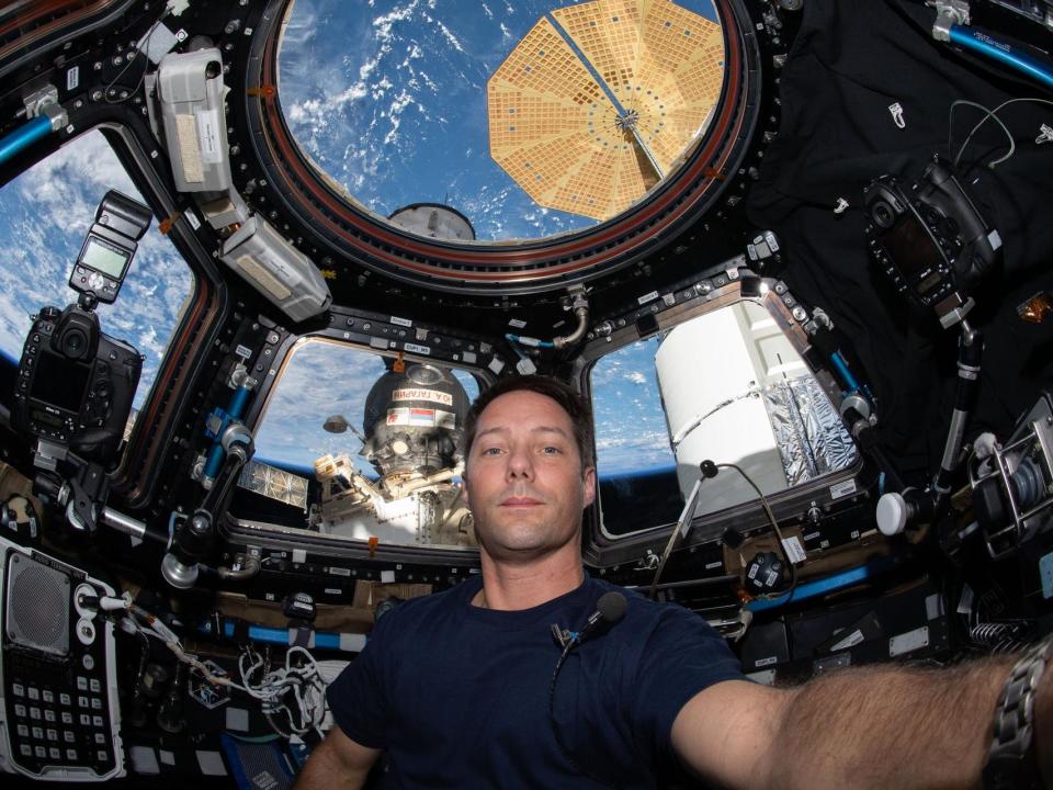 astronaut Thomas Pesquet selfie inside space station cupola windows overlooking blue cloudy earth