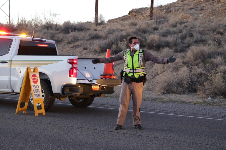 Navajo Police Officer Brandon Jim directs traffic during an April 1 checkpoint on the westbound lane of U.S. Highway 64 in Hogback.