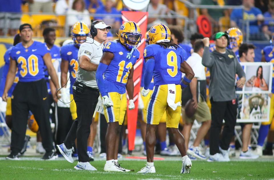 M.J. Devonshire (12) of the Pittsburgh Panthers celebrates with head coach Pat Narduzzi and teammate Brandon Hill (9) during the second half of the Backyard Brawl against the West Virginia Mountaineers