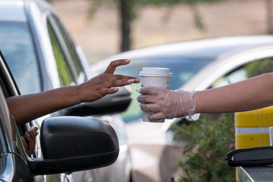 A Starbucks Corp. employee wearing protective gloves hands a customer an order from a drive-thru window at a store in Hercules, California, U.S., on Tuesday, April 7, 2020. Photographer: David Paul Morris/Bloomberg