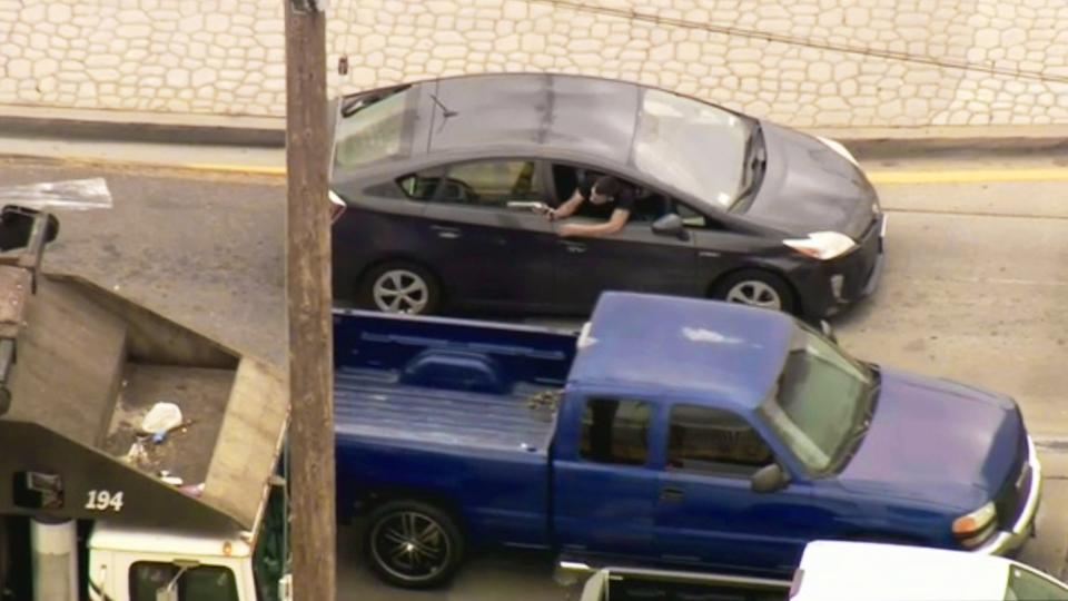 FILE - This Friday, May 10, 2019 image from video provided by FOX11 Los Angeles shows a man leaning out the window of a moving car, shooting at pursuing police vehicles during a wild car chase in the Los Angeles area. The car finally came to a halt in the Los Angeles suburb of Vernon, where the woman driver, who had blood on her shirt, surrendered. The gunman remained inside the car. Police say the man wounded in a car chase shootout in Southern California is suspected of killing a liquor store owner days earlier. The man was dragged unmoving from the car on Friday afternoon after a chase that began in Downey. (FOX11 Los Angeles via AP, File)