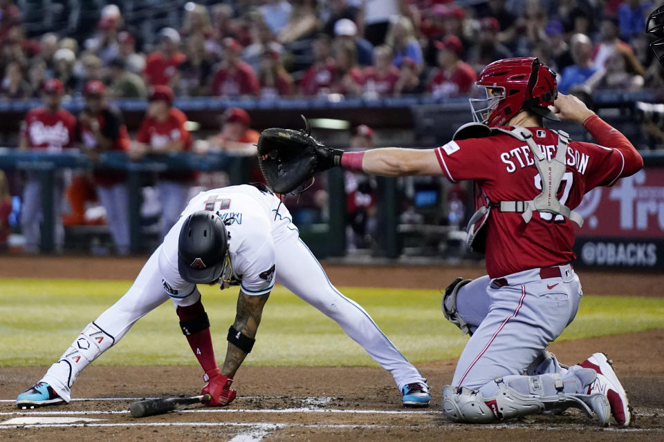 Arizona Diamondbacks' Ketel Marte, left, catches his balance after backing away from an inside pitch as Cincinnati Reds catcher Tyler Stephenson throws back to the pitcher during the first inning of a baseball game Sunday, Aug. 27, 2023, in Phoenix. (AP Photo/Ross D. Franklin)